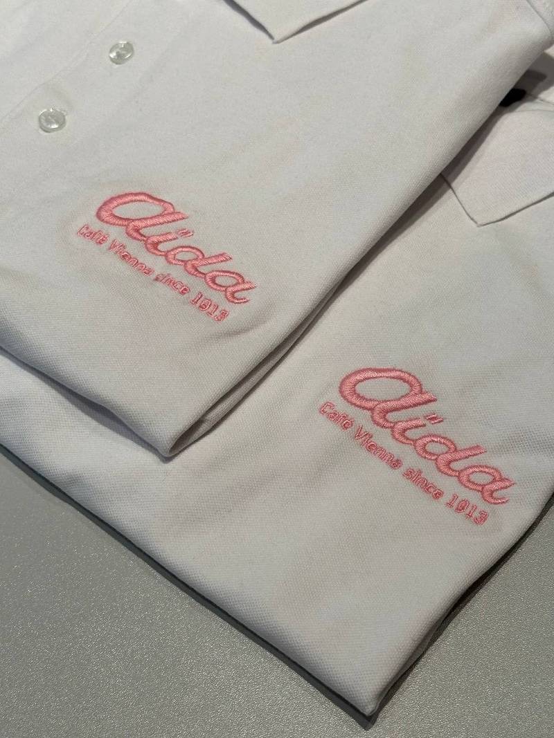 Aida Café Vienna Logo auf weißem Poloshirt gestickt, Gastrostickerei Wien