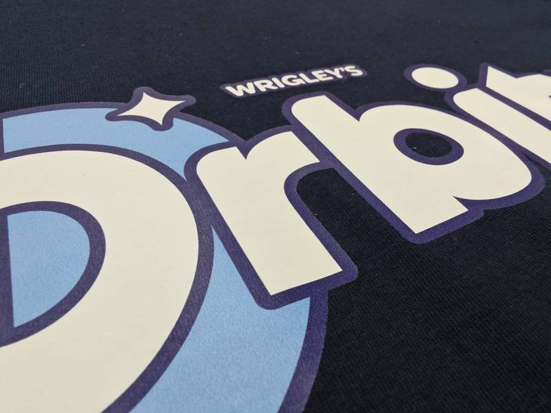 Wrigley's Orbit Logo, DTF-Druck Detail auf schwarzem Textil Wien