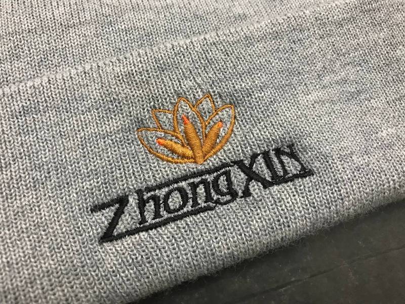 ZhongXin Logo auf grauer Haube gestickt, Lotus Stickerei Wien