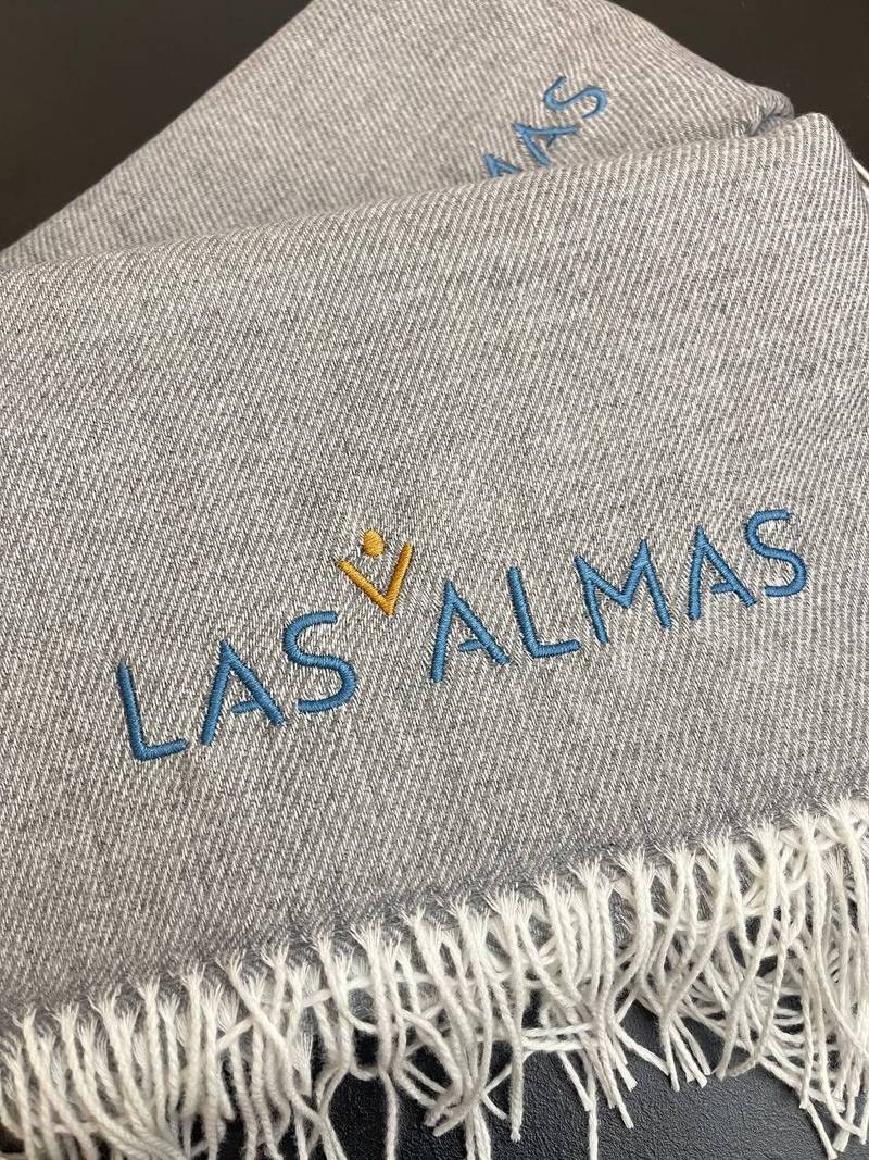 Las Almas Logo auf Decke gestickt, Textstickerei auf Wolldecke Wien